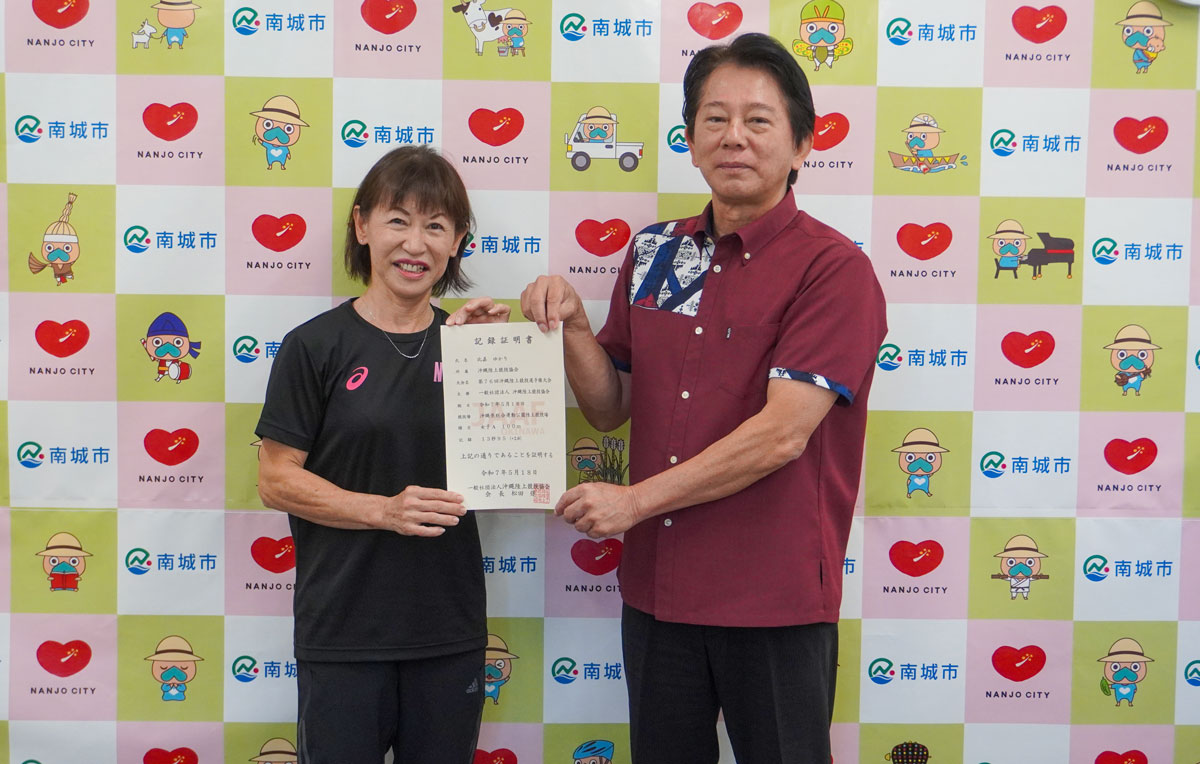 記録証明書を掲げる比嘉さんと具志堅教育長の写真