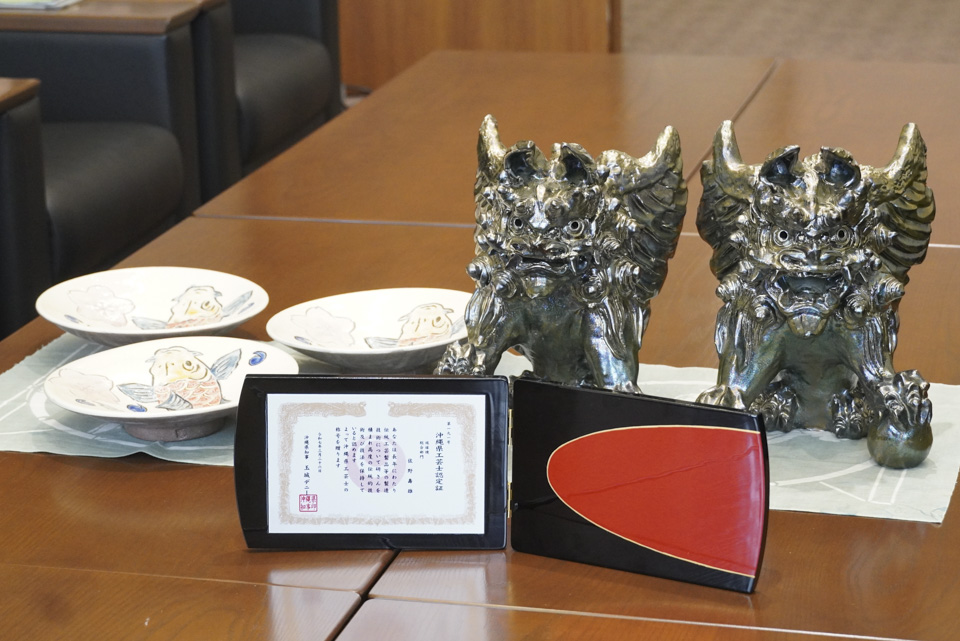 認定証と出品作品（左：丸皿、右：天子シーサー）